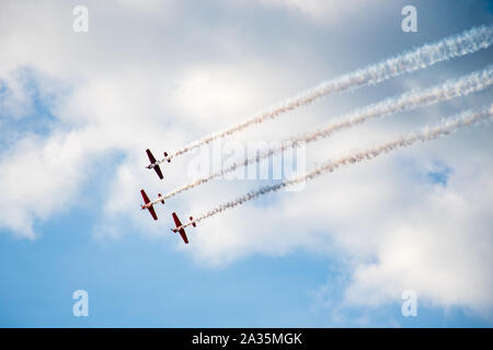 Acrobazia, air show. Il team di aeromobili di eseguire nel cielo con vecchi aerei e linee di disegno, il bianco delle nuvole e cielo blu Foto Stock