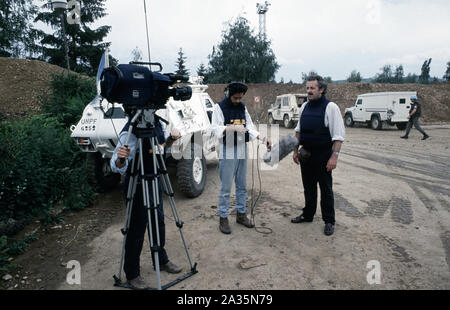 3rd giugno 1993 Durante l'assedio di Sarajevo: Jeremy Bowen (corrispondente BBC News) consegna le sue linee alla macchina fotografica nel parcheggio all'aeroporto di Sarajevo vicino ad un francese Panhard VBL. Foto Stock