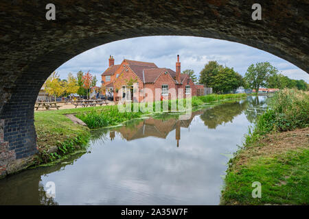 La sporca di anatra casa pubblica o pub accanto a Grantham Canal a Woolsthorpe dal Belvoir nel Lincolnshire incorniciata da un arco di alzaia bridge Foto Stock