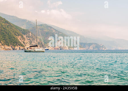 Monterosso Al Mare, Italia - 02 Settembre 2019: Mare yachts vicino la costa rocciosa con il verde delle montagne sullo sfondo a Monterosso Al Mare, Cinq Foto Stock