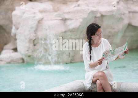 Bella donna guardando citymap turistico vicino a Fontana di Trevi, Roma, Italia. Felice ragazza godere di vacanza italiana vacanza in Europa. Foto Stock