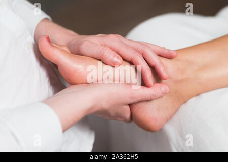 Professional masseur femmina dando riflessologia plantare per il piede della donna Foto Stock