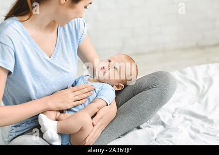 Giovane madre lulling i suoi adorabili baby boy su giri Foto Stock