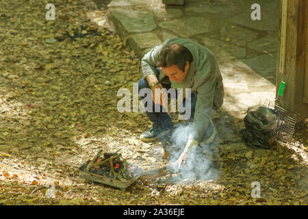 Foresta Belgrad, Istanbul, Turchia - 22 Settembre 2019: uomo di mezza età a partire di un barbecue portatile il fuoco sulla terra per un quotidiano relaxational un picnic Foto Stock