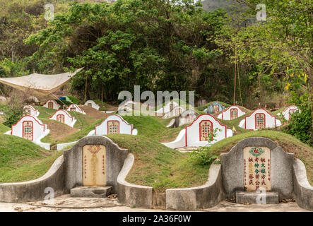 Phra Bang, Tailandia - 16 Marzo 2019: Chao Pho Khao Chalak cimitero Cinese. Gruppo di tombe di famiglia con la lapide beige con colorato mandarino lettere Foto Stock