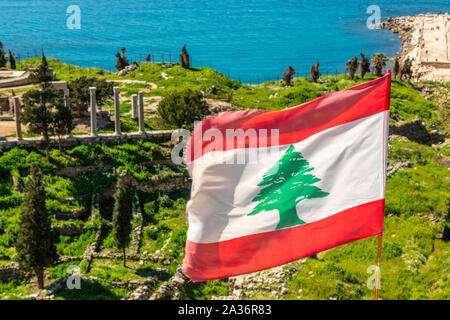 Libanesi di colore rosso e bianco con verde cedro bandiera sventola sul vento con il mare in background, Byblos, Libano Foto Stock