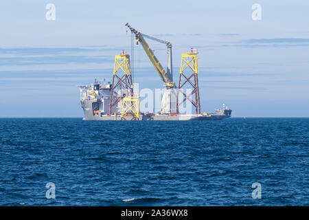 East Anglia uno Offshore Wind Farm in fase di costruzione con la pesante-lift costruzione nave, Boka sollevare, sollevando una delle giacche in luogo Foto Stock