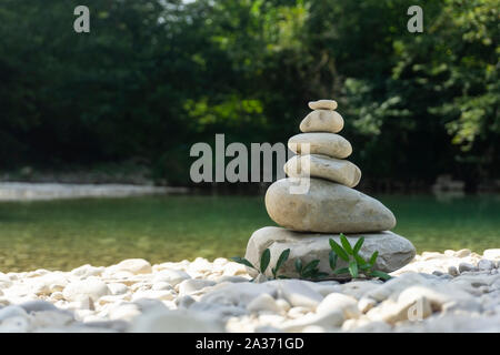 Armonia, equilibrio e la semplicità del concetto. Una piramide di pietra sullo sfondo di acqua di fiume. Semplice poise ciottoli, roccia scultura zen, una torre di rive Foto Stock