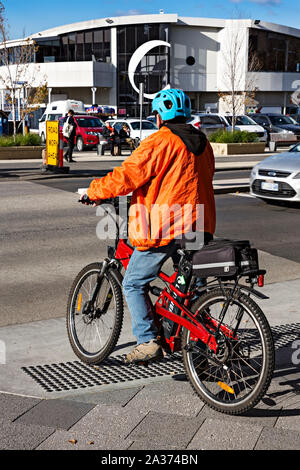 Hobart Australia / un uomo di mezza età in sella ad una bicicletta elettrica a Hobart in Tasmania.Hobart Australia / un uomo di mezza età che indossa una luminosa di sicurezza blu Foto Stock