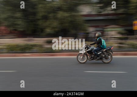 Panoramica tecnica di biker che sta per alcuni lavori a sera sulla strada Foto Stock