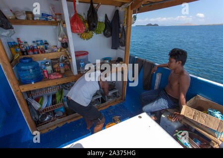 Labuanbajo, Indonesia - Agosto 17, 2015: sailor uomini per la cottura in una piccola barca nella parte anteriore della porta Foto Stock