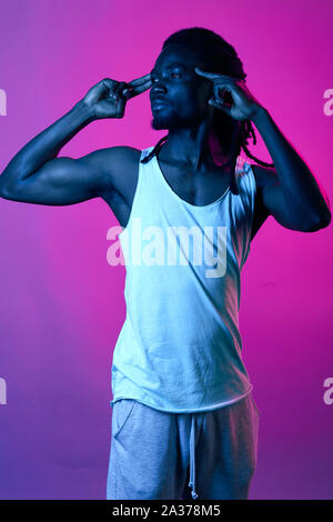 Musculat uomo bello con elegante dreadlocks toccando i suoi templi, gesto, il linguaggio del corpo, vicino la vista laterale verticale Foto Stock