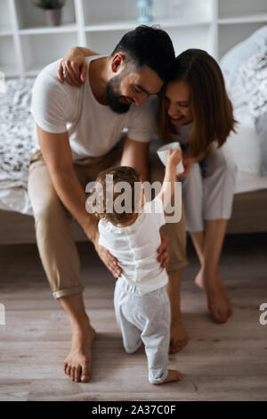 Attraente allegro genitori insegnare al bambino a piedi a piena lunghezza foto.i primi passi.concetto di felicità Foto Stock