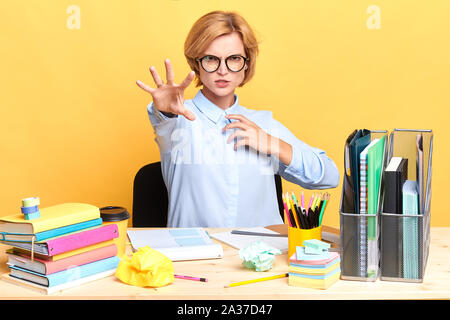 Funny giovane donna che mostra il suo palm, donna è divertirsi in ufficio. close up ritratto, isolato sfondo giallo, studio shot Foto Stock