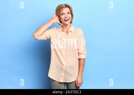 Ritratto di donna bella fingendo che parlando al telefono intelligente, sempre in conncetion, close up ritratto, mi chiamate in qualsiasi momento. isolato backgroun blu Foto Stock
