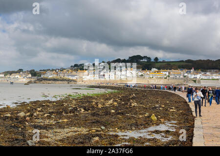 I visitatori e i turisti a piedi lungo la strada rialzata di marea a bassa marea tra Marazion e Saint Michaels Monte Isola in Cornovaglia Foto Stock