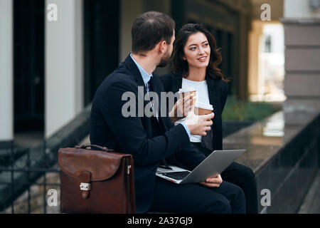 Riflessivo bella bruna eleganti donna e uomo bello parlare in strada, giovani coppe di contenimento avente una piacevole conversazione Foto Stock