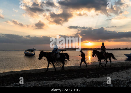 Gili Meno, Indonesia - 5 Agosto 2019: il turista a godere di passeggiate a cavallo sulla spiaggia al tramonto a Lombok in Indonesia Foto Stock