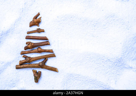 Piatto stilizzato laici albero di Natale fatto di piccoli ramoscelli sulla neve sullo sfondo. Spazio per il testo Foto Stock