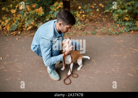 Giovane ragazzo attraente abbracciando abbracciando hs nice pet a piena lunghezza foto. Foto Stock