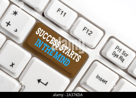 La scrittura della nota mostra il successo inizia nella mente. Il concetto di Business per avere pensieri positivi realizzare ciò che si desidera White tastiera PC con nota pape Foto Stock