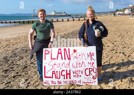 Bournemouth Dorset, Regno Unito. 6 ottobre 2019. La folla gregge a Bournemouth per la seconda giornata del Bournemouth Festival maratona per incitare e sostenere coloro che prendono parte alla Maratona e Mezza maratona su un soleggiato breezy day. Piano con me il cavalletto con il ridere di me con me il grido con me - vi sarà la mia cameriera di onore? Holding firmano per mostrare il destinatario in esecuzione nella mezza maratona. Lei ha detto di sì! Credito: Carolyn Jenkins/Alamy Live News Foto Stock