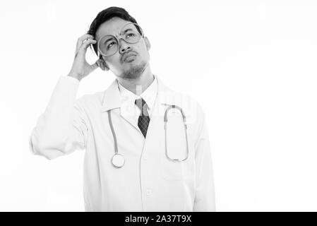 Studio shot del giovane uomo asiatico del pensiero medico mentre la testa di graffiatura Foto Stock