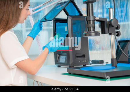Lavoratore di sesso femminile nel controllo di resina LCD / DLP / SLA stampante 3D nel laboratorio di tecnologia Foto Stock