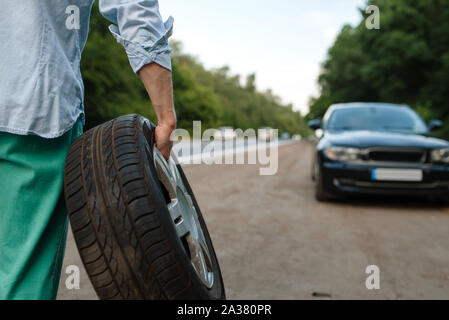 Ripartizione per auto, l'uomo mette la ruota di scorta Foto Stock