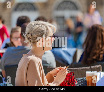 Udienza donna bionda di fumare sigarette in street cafe a Nancy, Francia Foto Stock