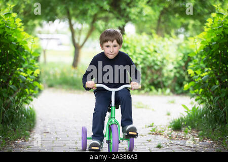 Il ragazzo su un triciclo.Child preschooler spin i pedali di una bicicletta giocattolo Foto Stock