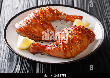 Popolare Cibo appiccicoso quartiere di pollo gambe con semi di sesamo servita con il limone closeup su una piastra sul tavolo orizzontale. Foto Stock