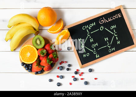 Molecola di glucosio sulla lavagna con un misto di frutta fresca insalata di legno su sfondo bianco, Dieta e scienze alimentari concetto Foto Stock