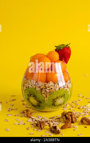 Budino di Chia con kiwi, oatmeals e melone o papaia le palline in un vetro luminoso su sfondo giallo. Detox e sana colazione superfoods concep Foto Stock