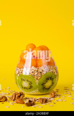 Budino di Chia con kiwi, oatmeals e melone o papaia le palline in un vetro luminoso su sfondo giallo. Detox e sana colazione superfoods concep Foto Stock