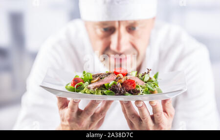 Lo chef nella cucina del ristorante o albergo tenendo la piastra con il cibo prima di servire. Foto Stock
