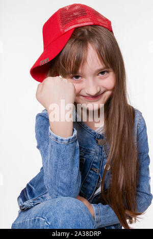 Allegro orologio bambina, guardando la telecamera, minaccia con un pugno Foto Stock