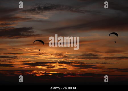 Coppia di powered parapendii in volo sopra il Sussex Southdowns durante un tramonto mozzafiato. Foto Stock