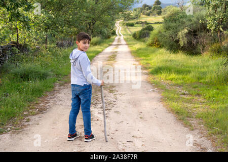 Ragazzo in piedi su un sentiero tenendo un bastone, Spagna Foto Stock