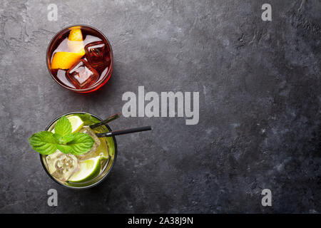 Due cocktail classico bicchieri sul tavolo di pietra. Negroni e mojito. Vista da sopra con copia spazio. Lay piatto Foto Stock