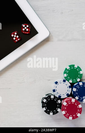 Poker chips e dadi rossi su un tablet con spazio per il testo. Scommesse online e giocare a poker su internet Foto Stock