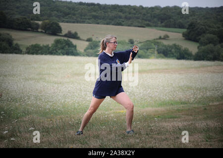 Donna pratica il Tai Chi in un campo in vacanza Foto Stock