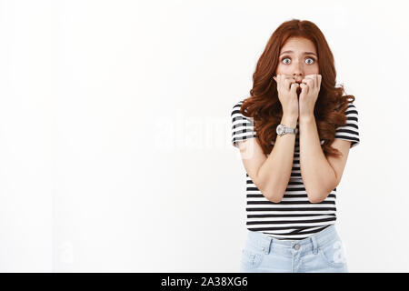 Spaventata scioccato e imbarazzato timido insicuro carino redhead donna in striped t-shirt, mordere le unghie, guardare fotocamera preoccupato, agitando di paura Foto Stock
