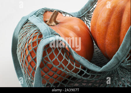 Zucche in shopping riutilizzabile eco-friendly borsa a rete su sfondo bianco. Foto Stock