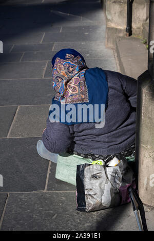 Vista posteriore dell'Est Europen mendicante seduto sul marciapiede su Lothian Road accanto a un Kozmetika Afrodita shopping bag. Foto Stock