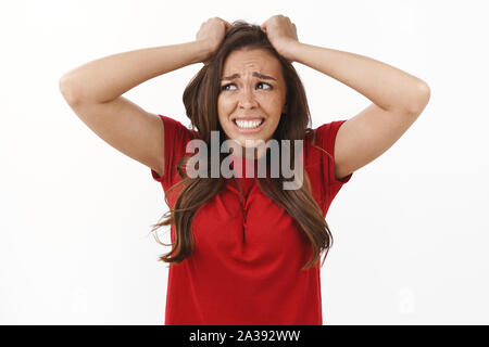 Ragazza in enormi problemi di panico. Sconvolto sconvolto brunette donna tirare i capelli dalla testa, smorfie di tristezza e delusione, accigliata piangere dal fastidioso Foto Stock