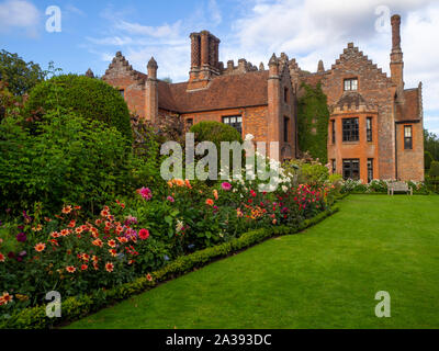 Verso sud confini dello stabilimento, Chenies Manor House e giardino in una bella serata ai primi di settembre.Prato, dalie, arbusti, dotate di architettura di Tudor. Foto Stock