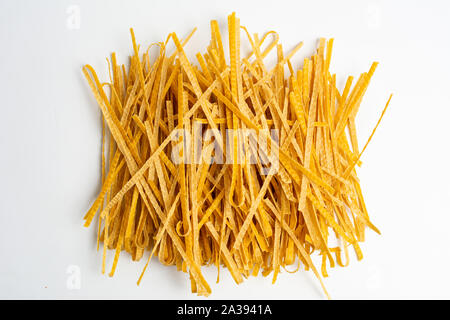 Fatta in Casa la pasta secca Tagliatelle su sfondo bianco Foto Stock