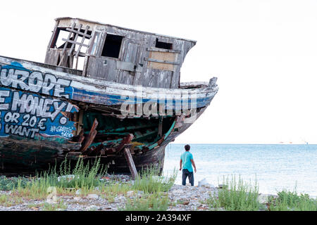 Un vecchio legno barca da pesca coperto di graffiti sul bacino di carenaggio. Foto Stock