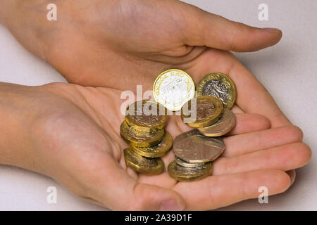 Due mani del bambino con British monete contro uno sfondo bianco Foto Stock